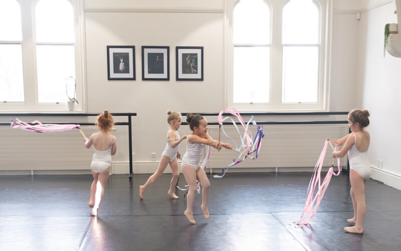 Happy children dancing with ribbons in ballet class