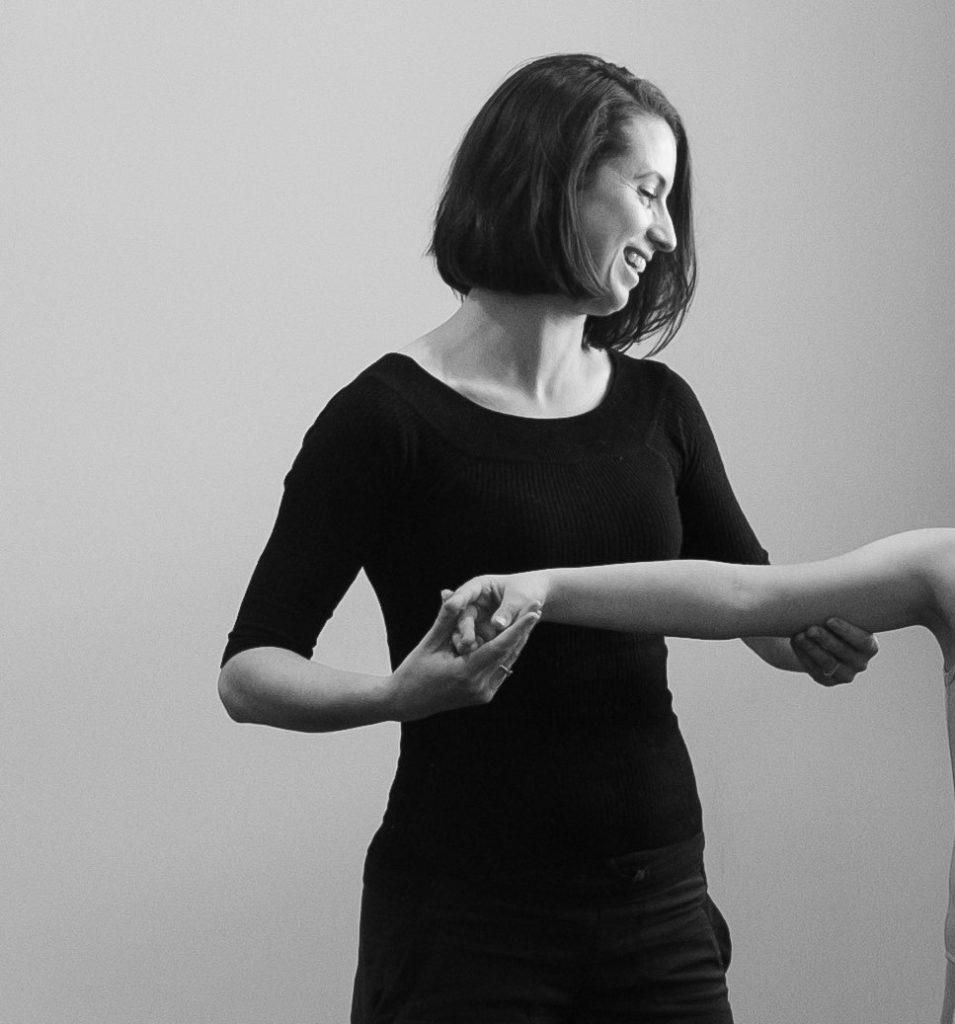 Dance teacher instructing child on correct arm placement